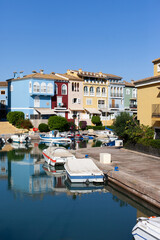 Fototapeta na wymiar Colorful buildings with canals and yachts in the resort. Travel destination in Mediterranean. European relaxing holidays. Colored houses reflected in the water of canal with parked boats.