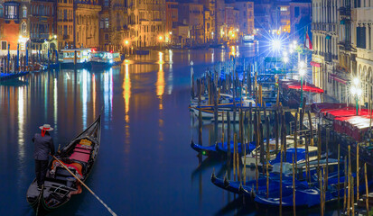 Venetian gondolier punting gondola through green canal waters at night - Venice Italy - obrazy, fototapety, plakaty