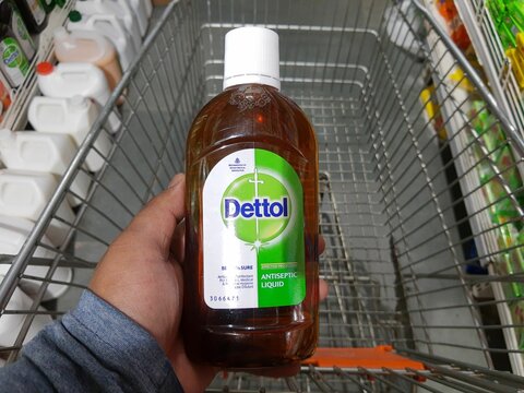 hands holding a big bottle of Dettol hand sanitizer