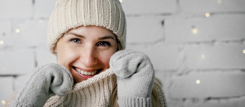 smiling woman in warm winter clothing. wool sweater, hat and mitten gloves. copy space