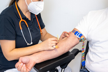Arzthelferin nimmt einem Patienten Blut ab