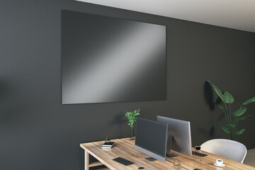 Contemporary coworking interior with empty black mock up screen on dark wall, desk, computer, chairs, decorative items, plants and supplies. Mock up, 3D Rendering.