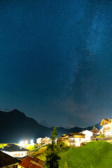 Beautiful night sky with stars and milky way visible above a small village in alps, Sauris, Italy