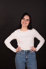 Portrait of a young and happy Armenian girl in a white jumper on a black background.