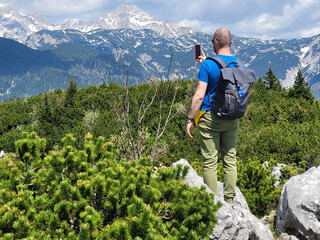 Happy man enjoys views of the alpine village in the mountains. Velika Planina or Big Pasture...