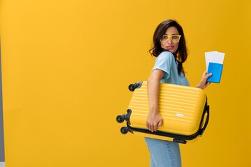 Traveler woman with yellow suitcase, passport and ticket in hand, paper plane, blue t-shirt and...