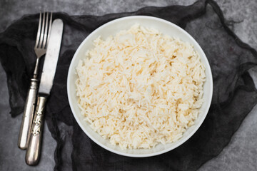 Boiled rice in a bowl on gray background.