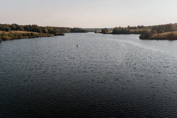 Fototapeta premium a girl on a sap board swims on the waves on the lake