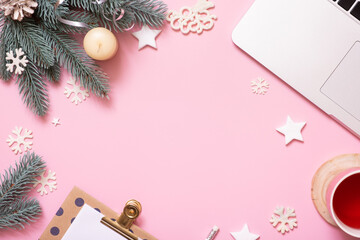Office work table with Christmas and New Year decoration top view, flat lay on pink background. Copy space for text during winter holidays