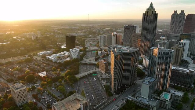 Downtown Atlanta cityscape in warm golden hour light. Aerial of traffic on interstate highway at rush hour among skyscraper buildings.