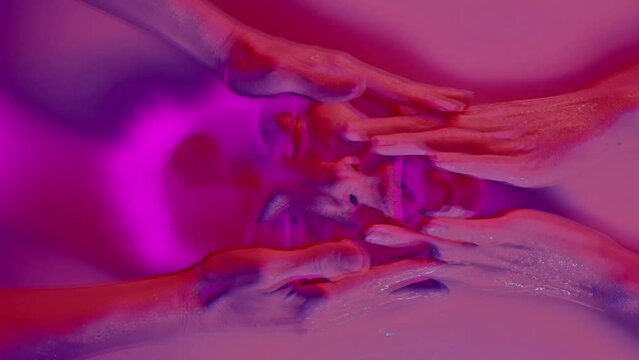Surreal portrait in psychedelic colors. The flow of multicolored paint madness of hands and face