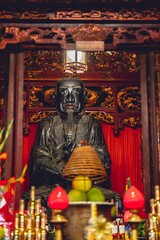 Vertikale Aufnahme eines buddhistischen Tempelaltars mit einer Konfuzius-Statue und Dekorationen in Vietnam