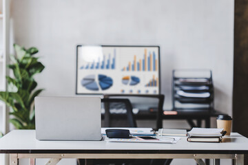 Empty workspace, no people, office desk, with laptop, calculator, graphs, documents on the table.