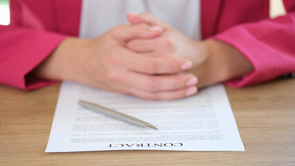 Businesswoman putting hands on contract agreement and silver pen