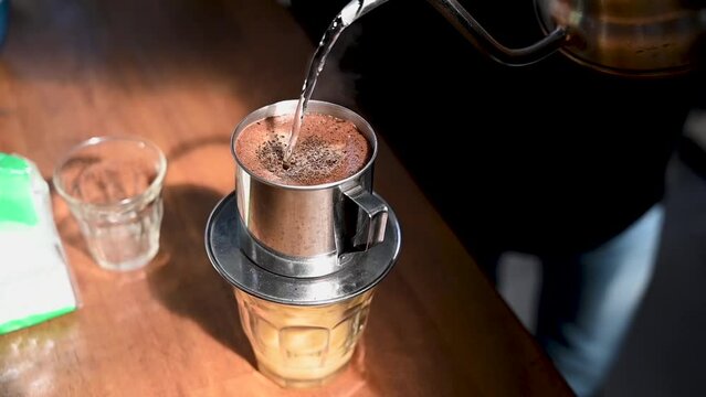 the process of serving Vietnamese drip coffee, from filtering drips to the coffee cup