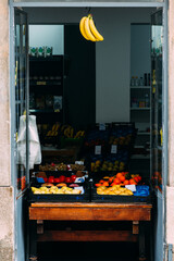 Entrance to a shop selling fresh fruit with bananas hanging from the doorway
