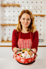 Portrait of a happy woman holding box with home made christmas cookies and smiling at the camera.