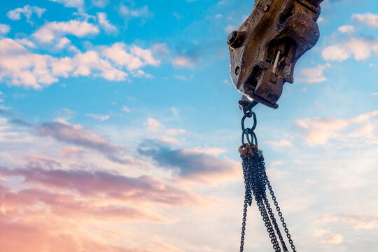 Steel chain attached to the excavator's arm. Lifting gear against blue sky with space for text as an abstract industrial background
