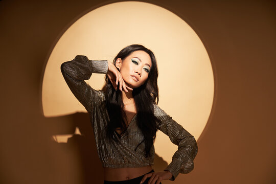 Vogue style portrait of sensual asian woman posing in studio in the spotlight