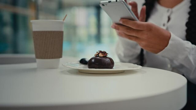 Close-up woman girl student food blogger hold mobile phone photographing trendy breakfast sweet chocolate dessert and coffee feel pleasure with delicious cupcake at cafe sharing photo in social media