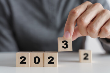 Man hand putting wooden cube block to change 2022 year to 2023 year. start to year 2023. happy new years concept.