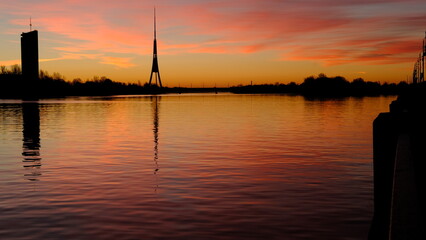 Reflection of the TV tower in the river against the background of dawn in Riga