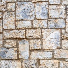 Stone wall made of marble blocks cut into various sizes. Rough natural background.