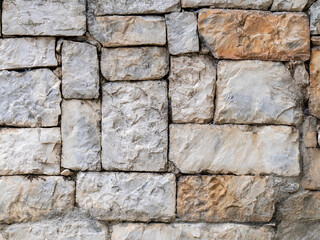 Stone wall made of marble blocks cut into various sizes. Rough natural background.
