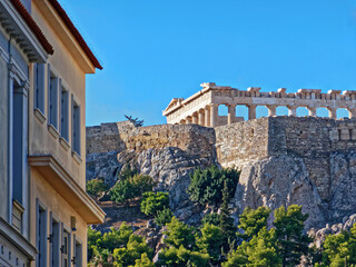 Fototapeta na wymiar Unusual view of Parthenon ancient temple from the street behind acropolis hill. A sunny day in Athens, Greece.