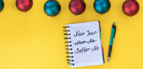 banner with Writing in a notebook New year, new me on yellow background with Christmas balls. Happy new year quote. Top view. Flat lay
