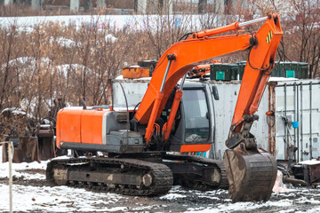 Orange crawler excavator at a construction site at winter