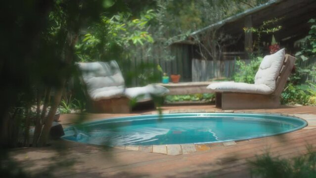 Two chairs with soft white cushions next to a small pool. Slow motion, shallow depth of field. 