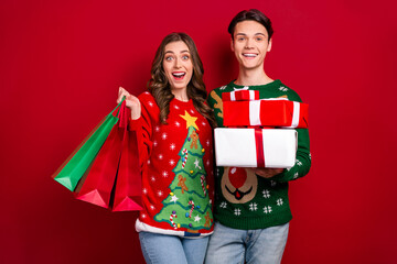 Photo of two excited funny people hold shopping bags pile stack newyear giftbox isolated on red color background