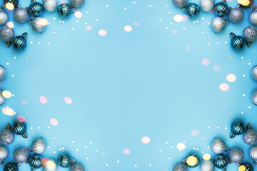 Christmas baubles on blue background. Frame border. Christmas New Year composition background blue grey silver colored. Christmas lights. Minimal concept.