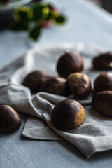 Step by step process of making roasted chestnuts. Heap of raw chestnuts on linen cloth.