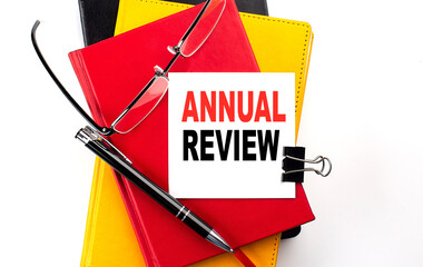 ANNUAL REVIEW text written on a sticky on colorful notebooks