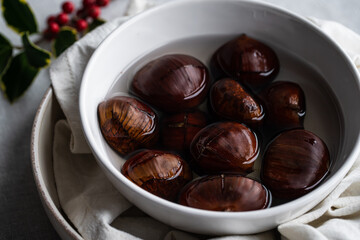 Step by step process of making roasted chestnuts. Chestnuts soaked in water before baking.