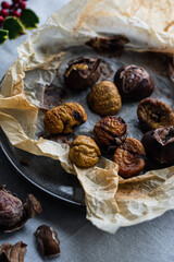 Step by step process of making roasted chestnuts. Peeled roasted chestnuts on baking paper on plate.