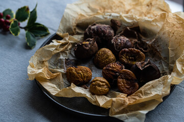 Step by step process of making roasted chestnuts. Peeled roasted chestnuts on baking paper on plate.
