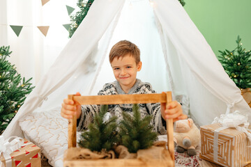 A little boy lying in a children's wigwam decorated for Christmas © fotofabrika