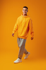 Fototapeta premium Full length portrait of young man standing on yellow background