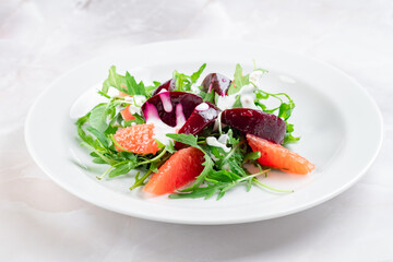 Salad with boiled beetroot, grapefruit, arugula and cream cheese. Beetroot slices with green salad