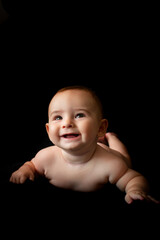 Bebé tumbado sonriente con fondo negro - obrazy, fototapety, plakaty