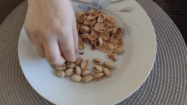 A person removes the shell from a pistachio