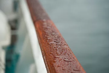 Deurstickers Regentropen auf der hölzernen Reling eines Schiffes © Mario Schmidt