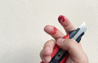 There is a red bloody wound on the finger, an accidental knife or cutter cut on the finger of a man...