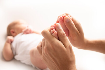 Obraz na płótnie Canvas Mother is doing massage on her baby foot. Close up baby feet in mother hands on a white background. Prevention of flat feet, development, muscle tone, dysplasia. Family, love, care, and health concept