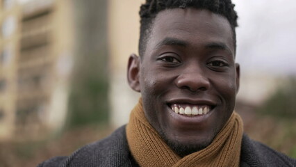 Charismatic happy black African young man smiling outside wearing scarf and winter coat