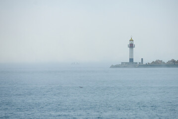 Lighthouse in a foggy sea at sunrise