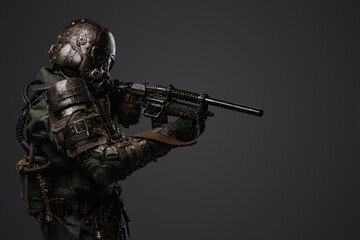 Portrait of military man in post apocalypse style dressed in armored suit aiming shotgun.